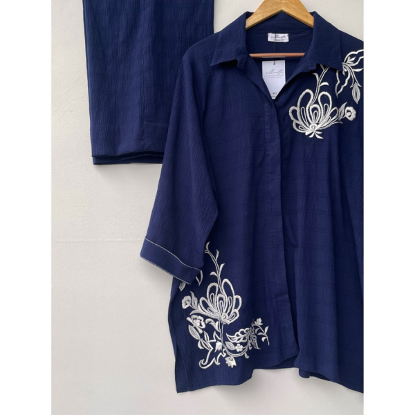 White floral embroidery detail on deep blue textured georgette fabric